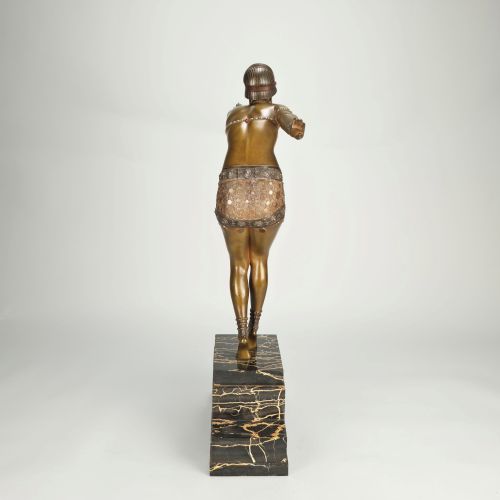 fig 7. An Art Deco gilt bronze sculpture depicting a female dancer in an elaborate costume posed dynamically on a stepped black marbled base.