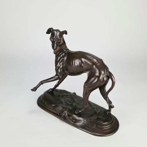 fig 3. A dark brown patinated bronze sculpture depicting a slender greyhound standing on an oval base looking back towards a fly on its hindquarters.