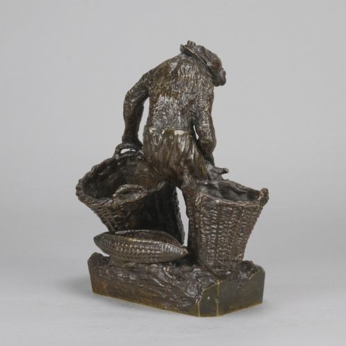 fig 4. A dark patinated bronze sculpture depicting an anthropomorphic monkey wearing trousers and a cap, standing beside two large woven baskets on a rectangular base.
