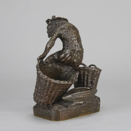 fig 5. A dark patinated bronze sculpture depicting an anthropomorphic monkey wearing trousers and a cap, standing beside two large woven baskets on a rectangular base.