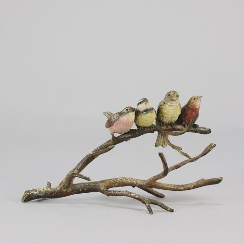 fig 1. An early 20th-century cold-painted bronze sculpture depicting four colourful small birds perched along a textured tree branch.
