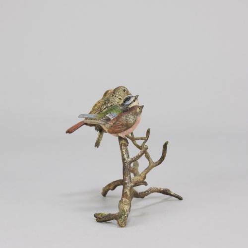 fig 3. An early 20th-century cold-painted bronze sculpture depicting four colourful small birds perched along a textured tree branch.