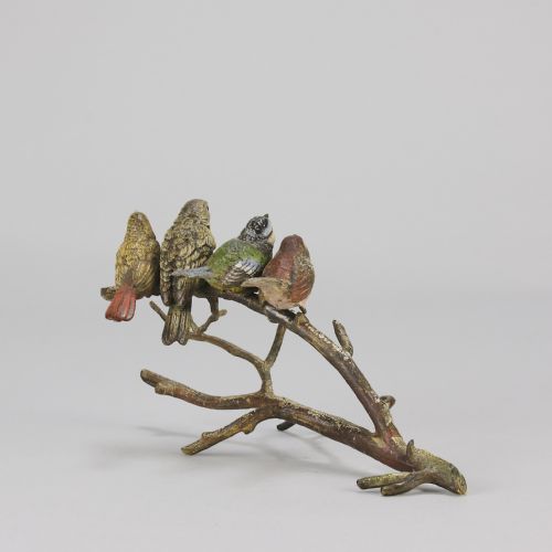 fig 4. An early 20th-century cold-painted bronze sculpture depicting four colourful small birds perched along a textured tree branch.