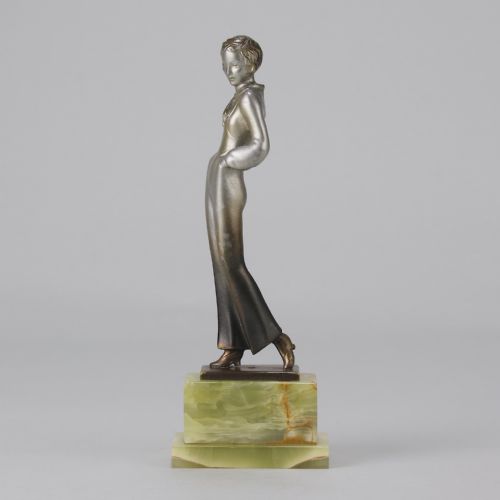 fig 1. An Art Deco silvered metal statuette of a woman in modern trousers standing on a tiered green onyx base.