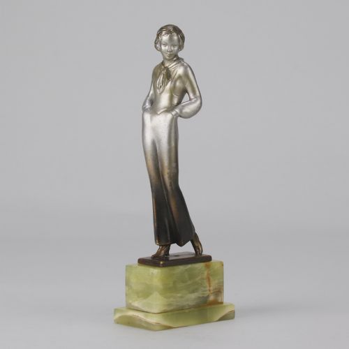fig 3. An Art Deco silvered metal statuette of a woman in modern trousers standing on a tiered green onyx base.