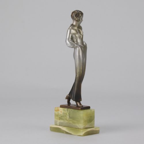 fig 4. An Art Deco silvered metal statuette of a woman in modern trousers standing on a tiered green onyx base.