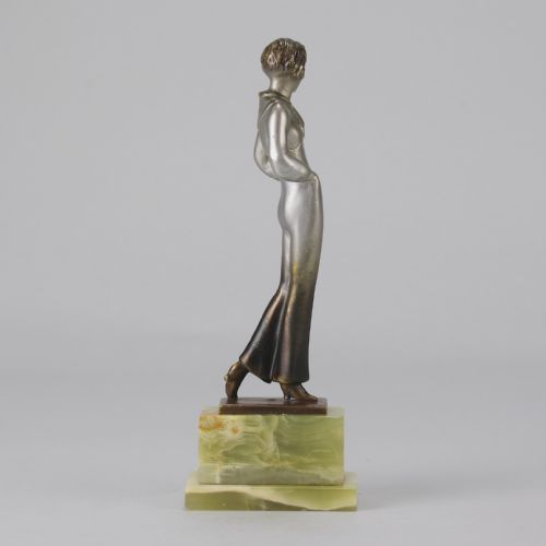 fig 5. An Art Deco silvered metal statuette of a woman in modern trousers standing on a tiered green onyx base.
