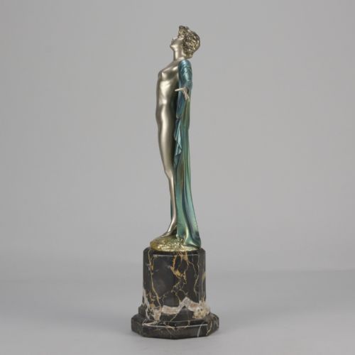 fig 2. An Art Deco cold-painted bronze sculpture depicting a silver female figure with outstretched arms wearing a teal cape, mounted on a black veined marble pedestal.