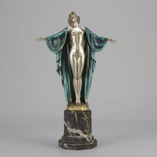 fig 4. An Art Deco cold-painted bronze sculpture depicting a silver female figure with outstretched arms wearing a teal cape, mounted on a black veined marble pedestal.