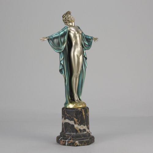 fig 5. An Art Deco cold-painted bronze sculpture depicting a silver female figure with outstretched arms wearing a teal cape, mounted on a black veined marble pedestal.
