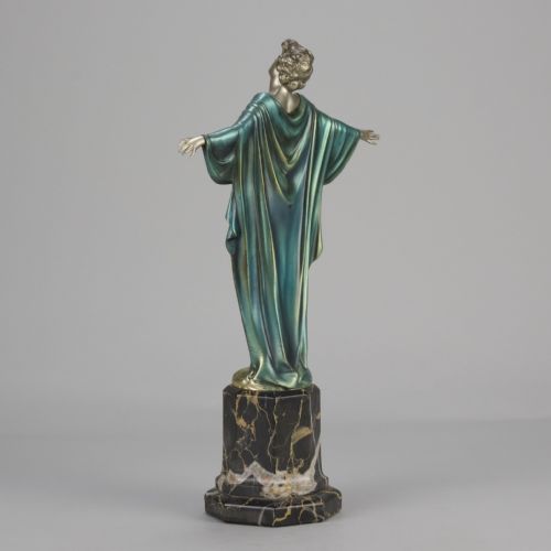 fig 8. An Art Deco cold-painted bronze sculpture depicting a silver female figure with outstretched arms wearing a teal cape, mounted on a black veined marble pedestal.