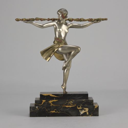 fig 1. An Art Deco cold-painted metal sculpture of a female dancer holding a staff, posed dynamically on a stepped black and gold marble base.