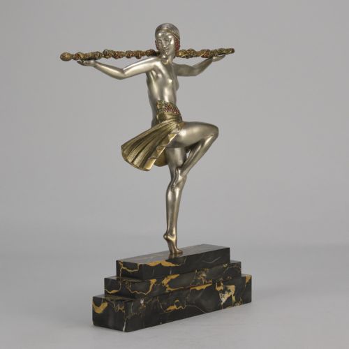 fig 2. An Art Deco cold-painted metal sculpture of a female dancer holding a staff, posed dynamically on a stepped black and gold marble base.