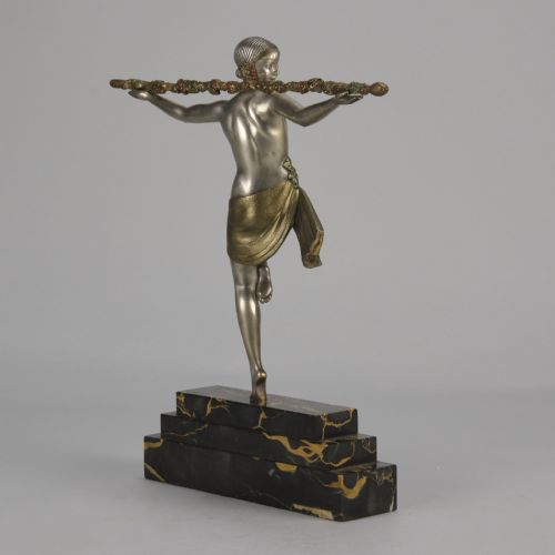 fig 4. An Art Deco cold-painted metal sculpture of a female dancer holding a staff, posed dynamically on a stepped black and gold marble base.