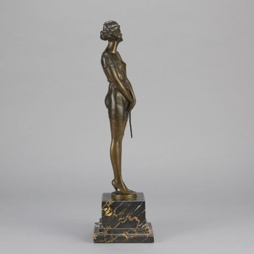 fig 3. An Art Deco bronze statue of a standing woman holding a crop, mounted on a square black marble pedestal.