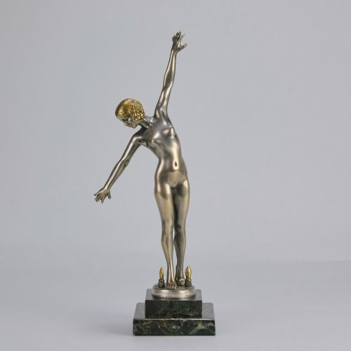 fig 1. An Art Deco silver-toned cold-painted bronze sculpture depicting a standing female dancer raised on a dark green marble pedestal base.