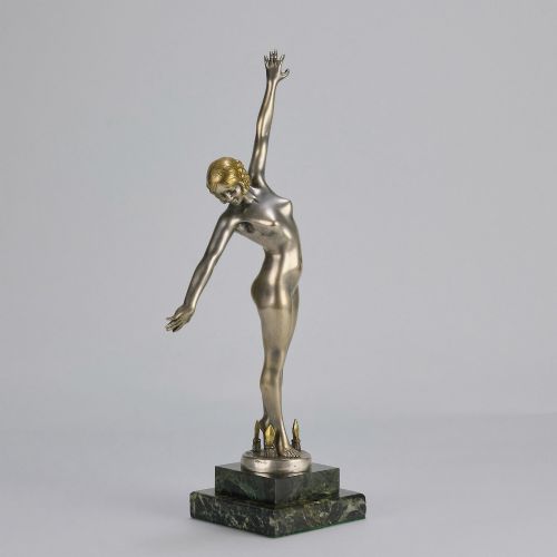 fig 2. An Art Deco silver-toned cold-painted bronze sculpture depicting a standing female dancer raised on a dark green marble pedestal base.