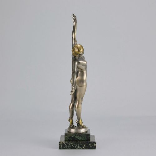 fig 3. An Art Deco silver-toned cold-painted bronze sculpture depicting a standing female dancer raised on a dark green marble pedestal base.