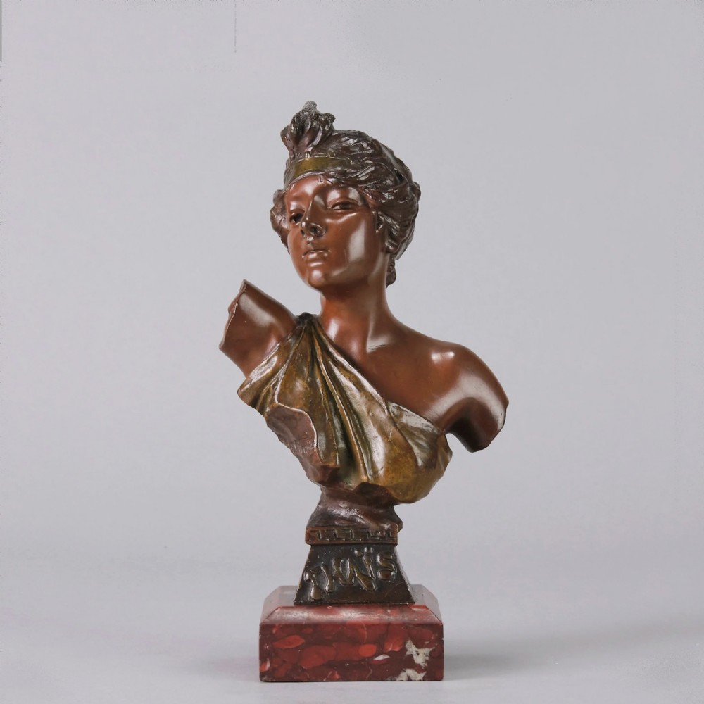 An Art Nouveau bronze bust of a woman titled Thais mounted on a red marble base.