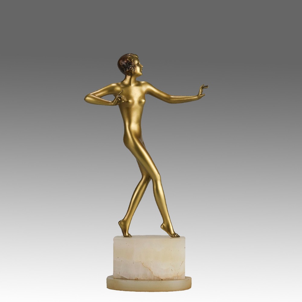 An Art Deco cold-painted bronze figurine depicting a slender female dancer posed on a square onyx base.