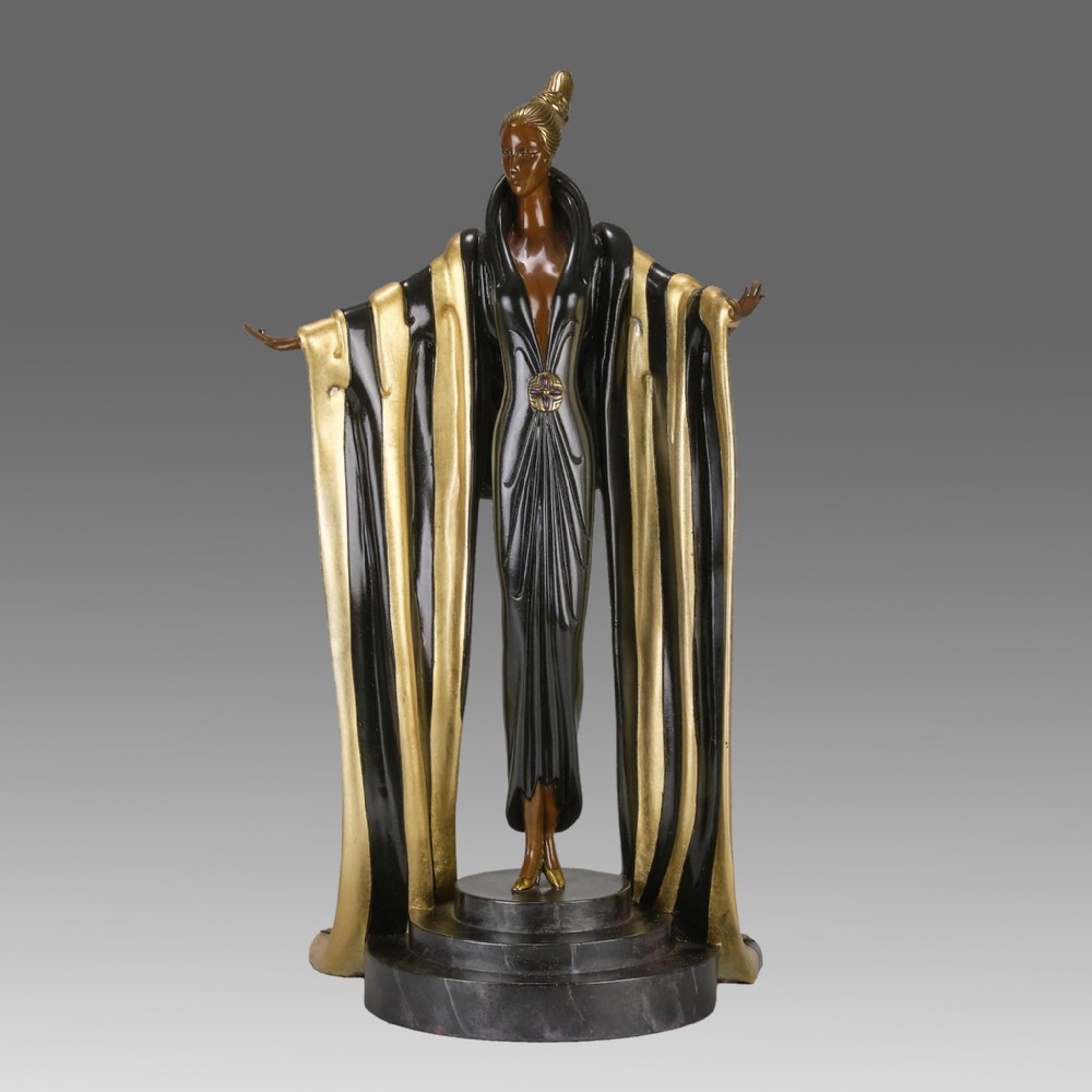 An Art Deco cold-painted bronze figurine depicting a female figure in a floor-length black and gold robe standing on a stepped dark base.