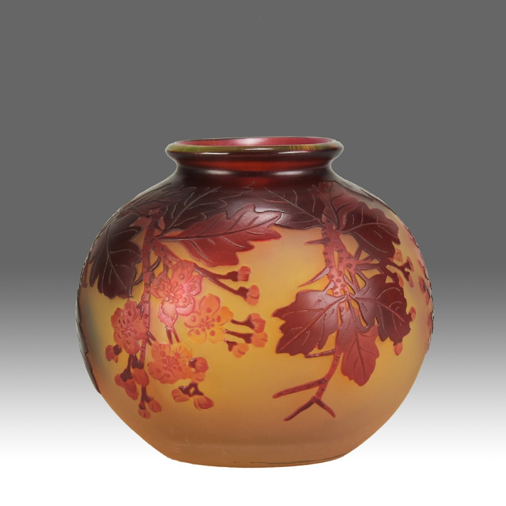 A spherical Art Nouveau cameo glass vase featuring etched red apple blossom branches over a frosted amber background.
