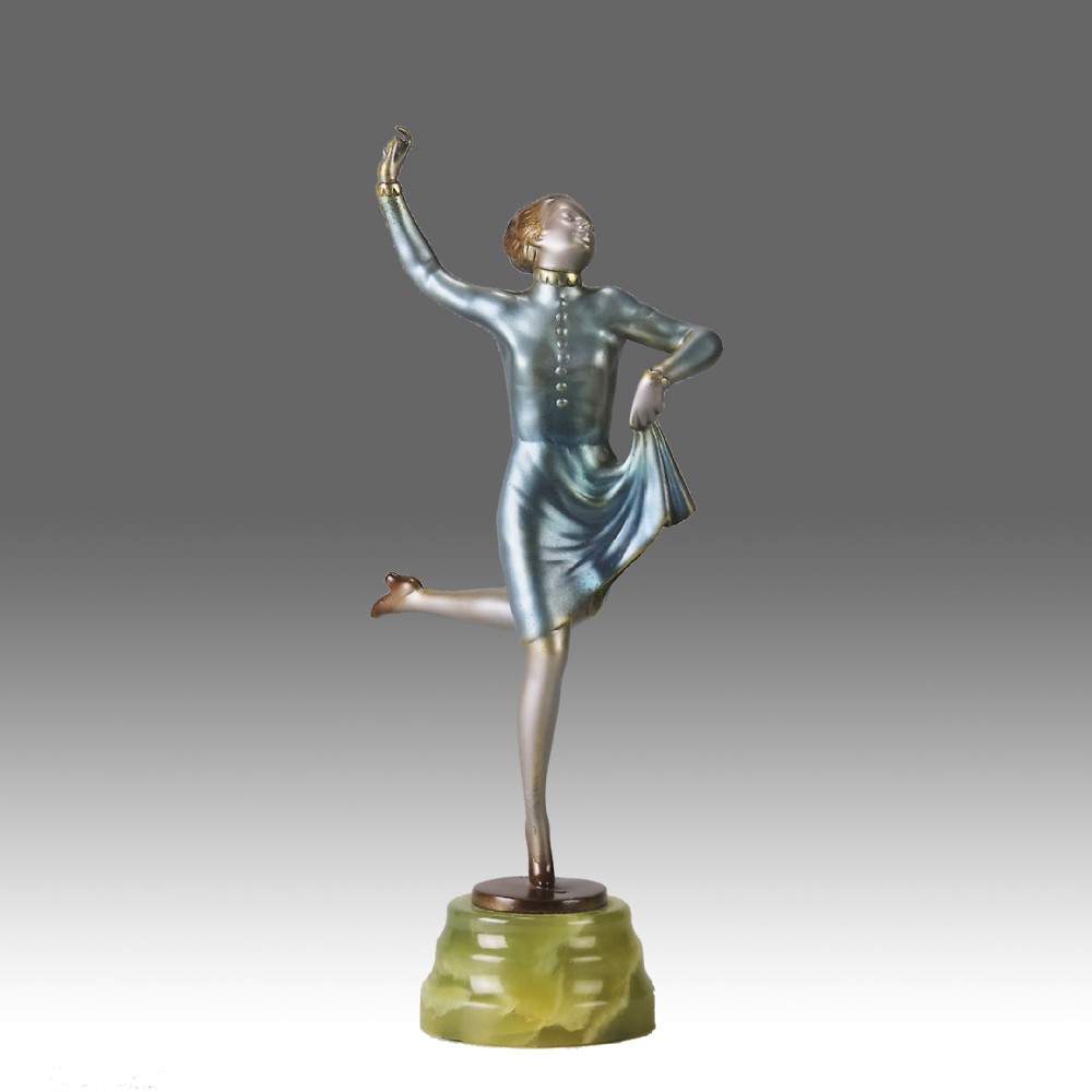 An Art Deco cold-painted bronze figurine depicting a female dancer poised on one foot atop a carved green onyx pedestal.