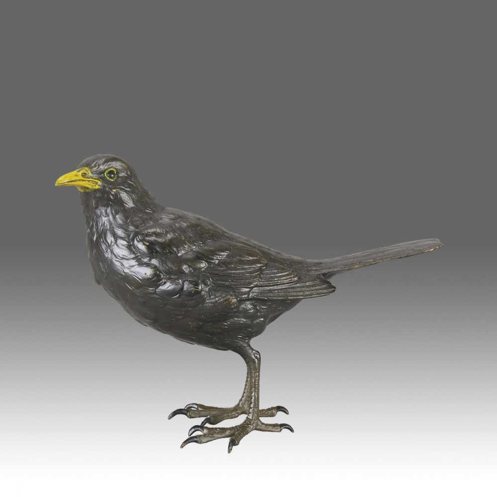 An early 20th-century cold-painted bronze figurine depicting a standing blackbird with dark plumage and a bright yellow beak.