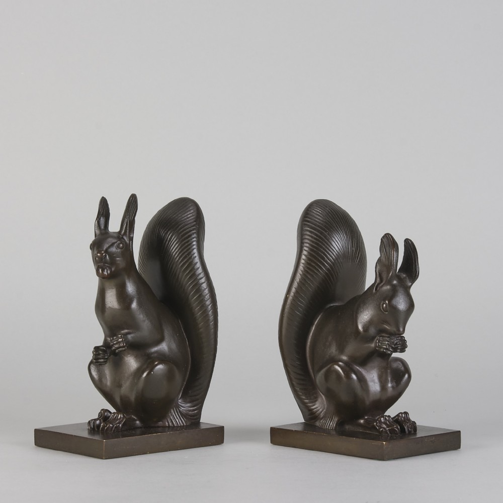 A pair of early 20th-century dark brown cast bronze bookends featuring seated squirrels with raised tails mounted on rectangular bases.