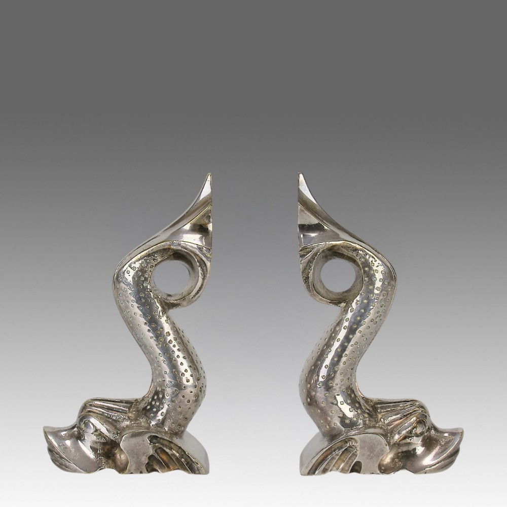 A pair of silvered metal bookends sculpted in the shape of upright stylised fish with textured scales and curved tails.