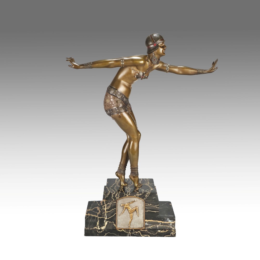 An Art Deco gilt bronze sculpture depicting a female dancer in an elaborate costume posed dynamically on a stepped black marbled base.