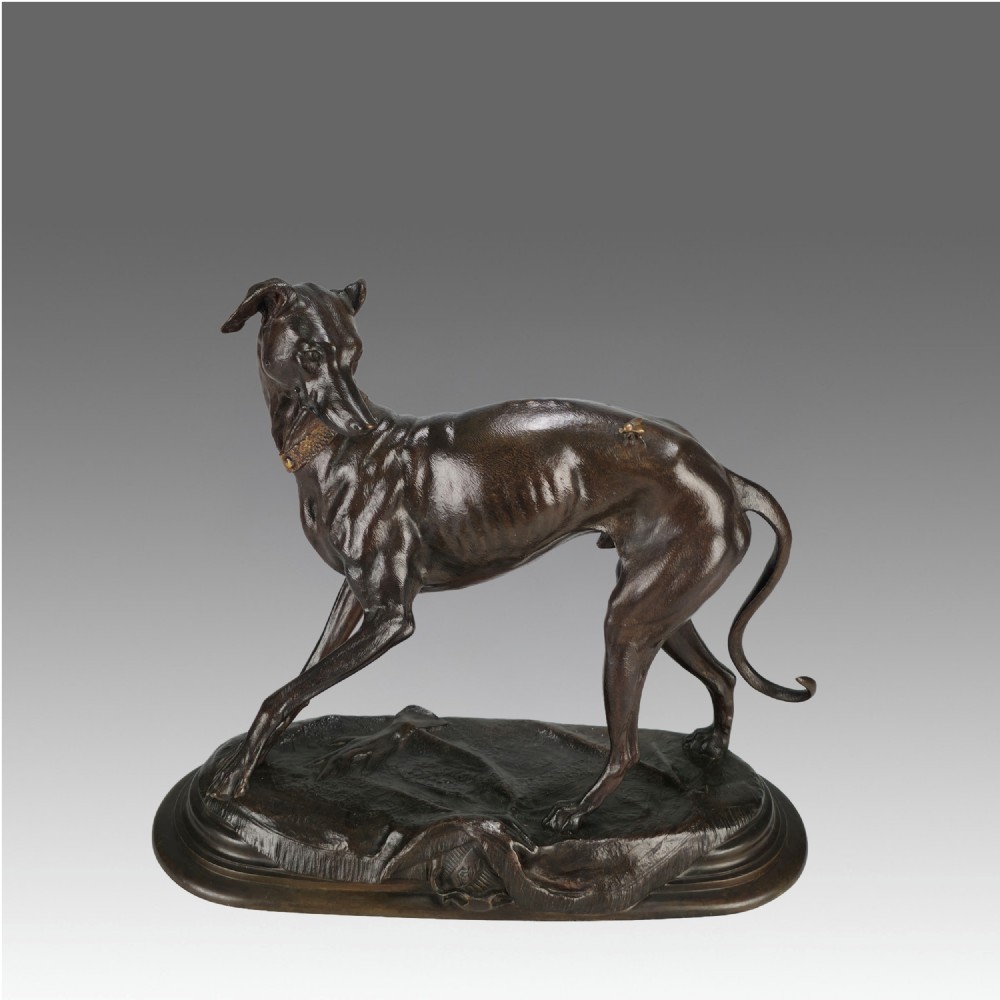 A dark brown patinated bronze sculpture depicting a slender greyhound standing on an oval base looking back towards a fly on its hindquarters.