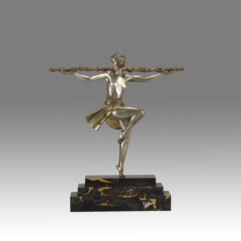 An Art Deco cold-painted metal sculpture of a female dancer holding a staff, posed dynamically on a stepped black and gold marble base.