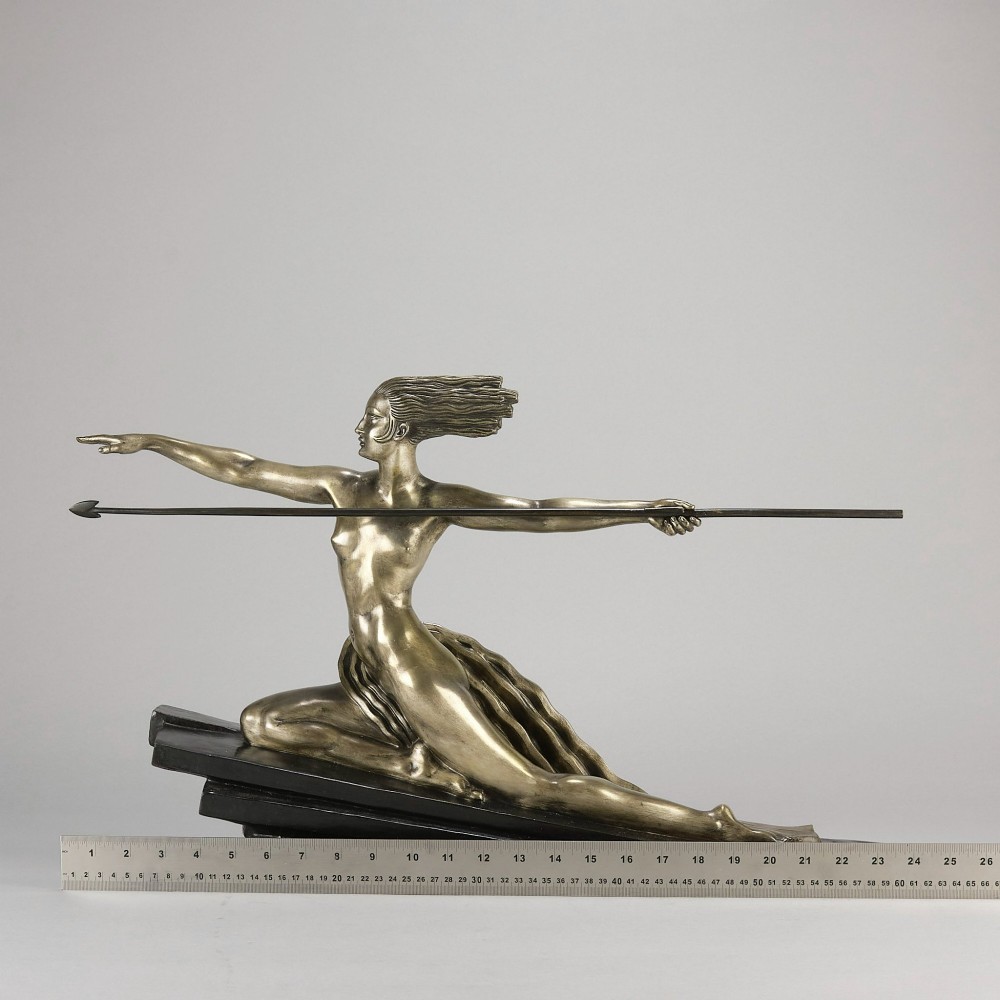 An Art Deco silvered metal sculpture depicting a stylized female archer holding a spear, mounted on a stepped black base. View X