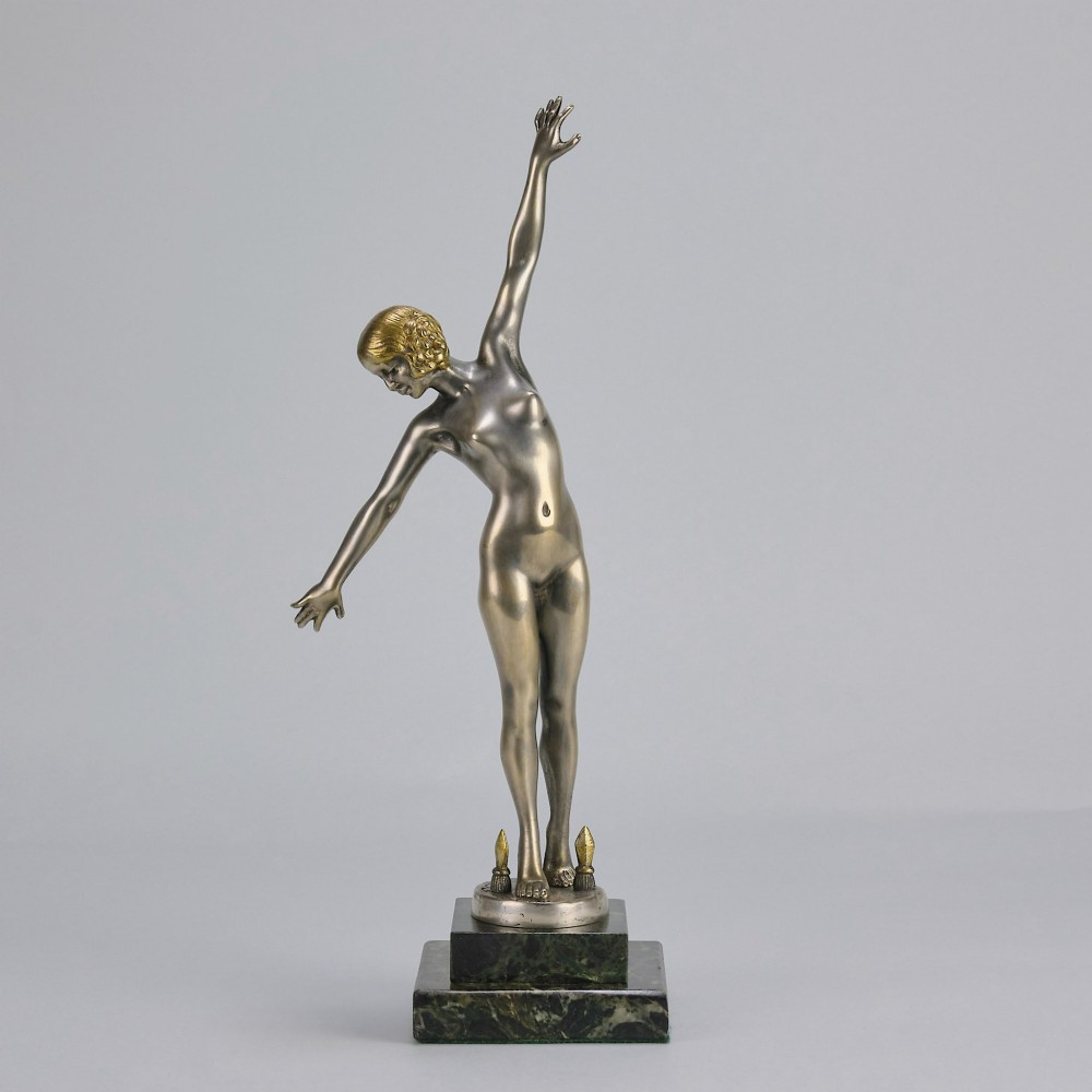 An Art Deco silver-toned cold-painted bronze sculpture depicting a standing female dancer raised on a dark green marble pedestal base. View II