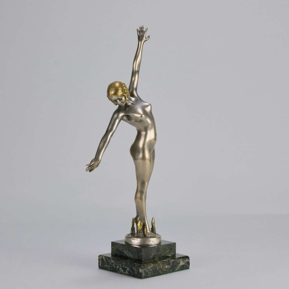 An Art Deco silver-toned cold-painted bronze sculpture depicting a standing female dancer raised on a dark green marble pedestal base. View III