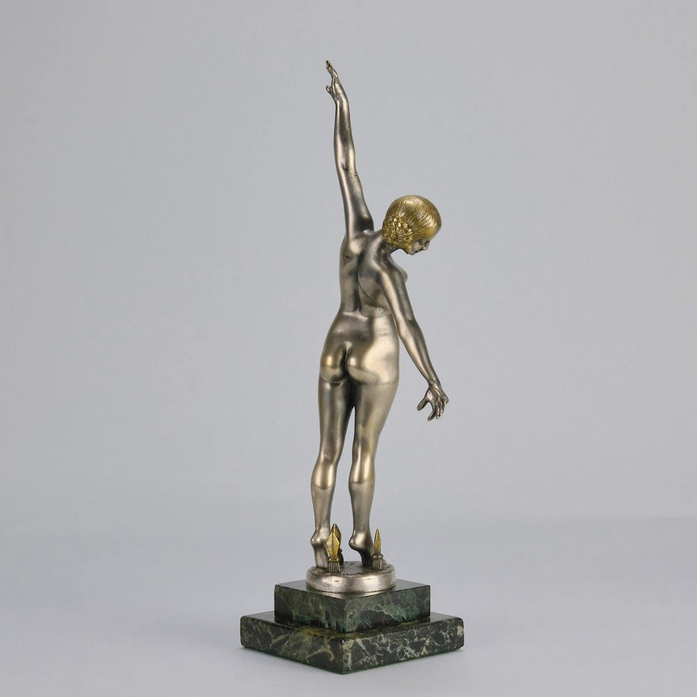 An Art Deco silver-toned cold-painted bronze sculpture depicting a standing female dancer raised on a dark green marble pedestal base. View V