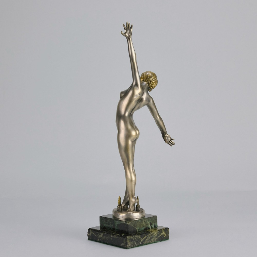 An Art Deco silver-toned cold-painted bronze sculpture depicting a standing female dancer raised on a dark green marble pedestal base. View VII