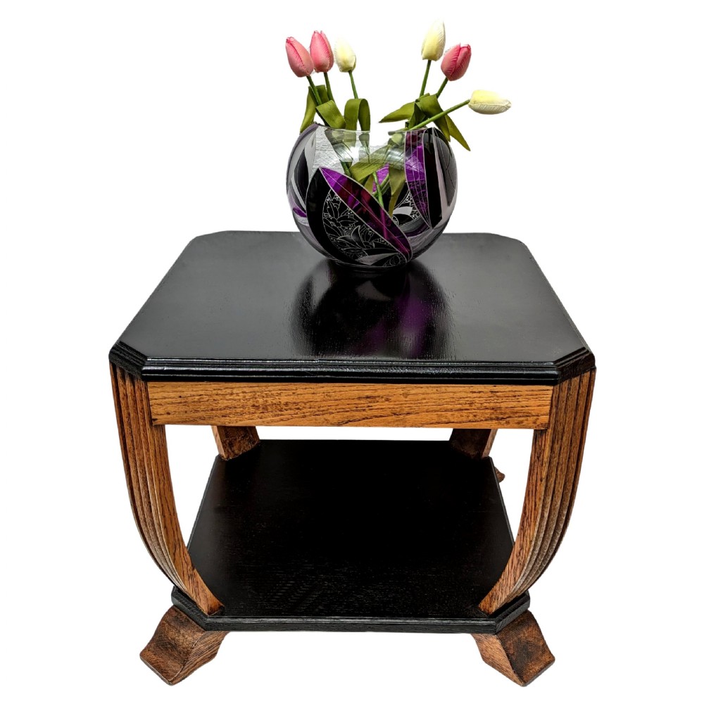 An Art Deco two-tiered occasional table featuring an ebonised black top surface and lower shelf contrasted with solid oak reeded legs.