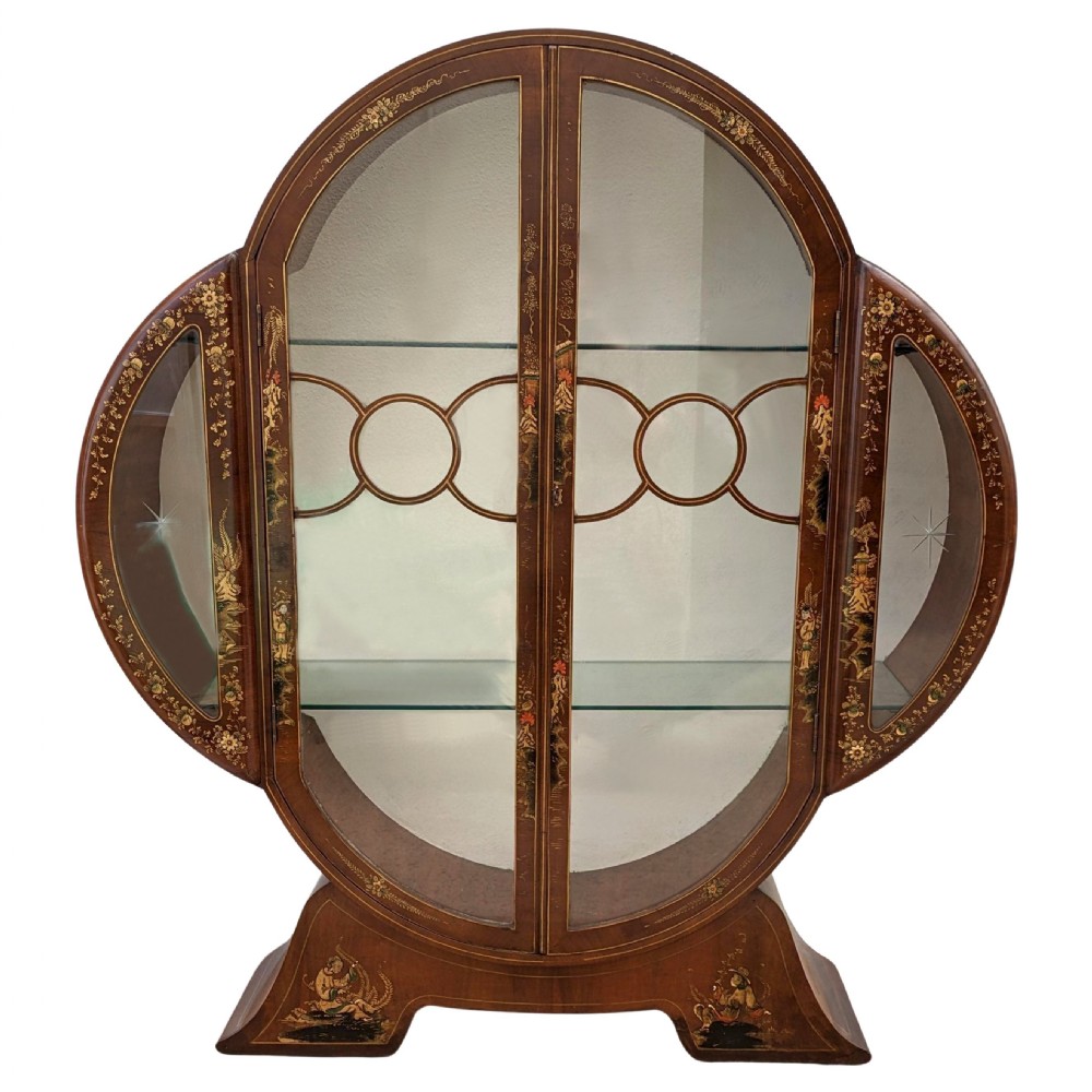 A 1930s Art Deco mahogany display cabinet featuring a circular silhouette with hand-painted gilt Chinoiserie details and glazed double doors.