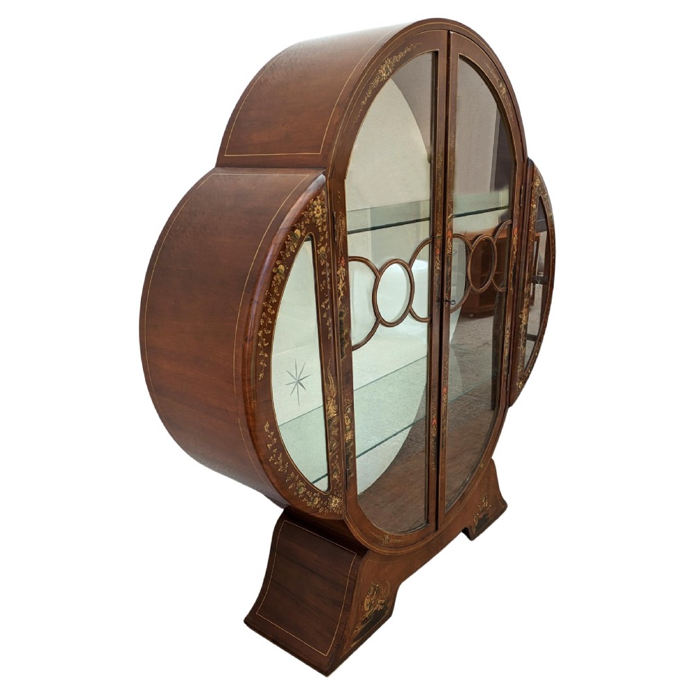 A 1930s Art Deco mahogany display cabinet featuring a circular silhouette with hand-painted gilt Chinoiserie details and glazed double doors. View VI