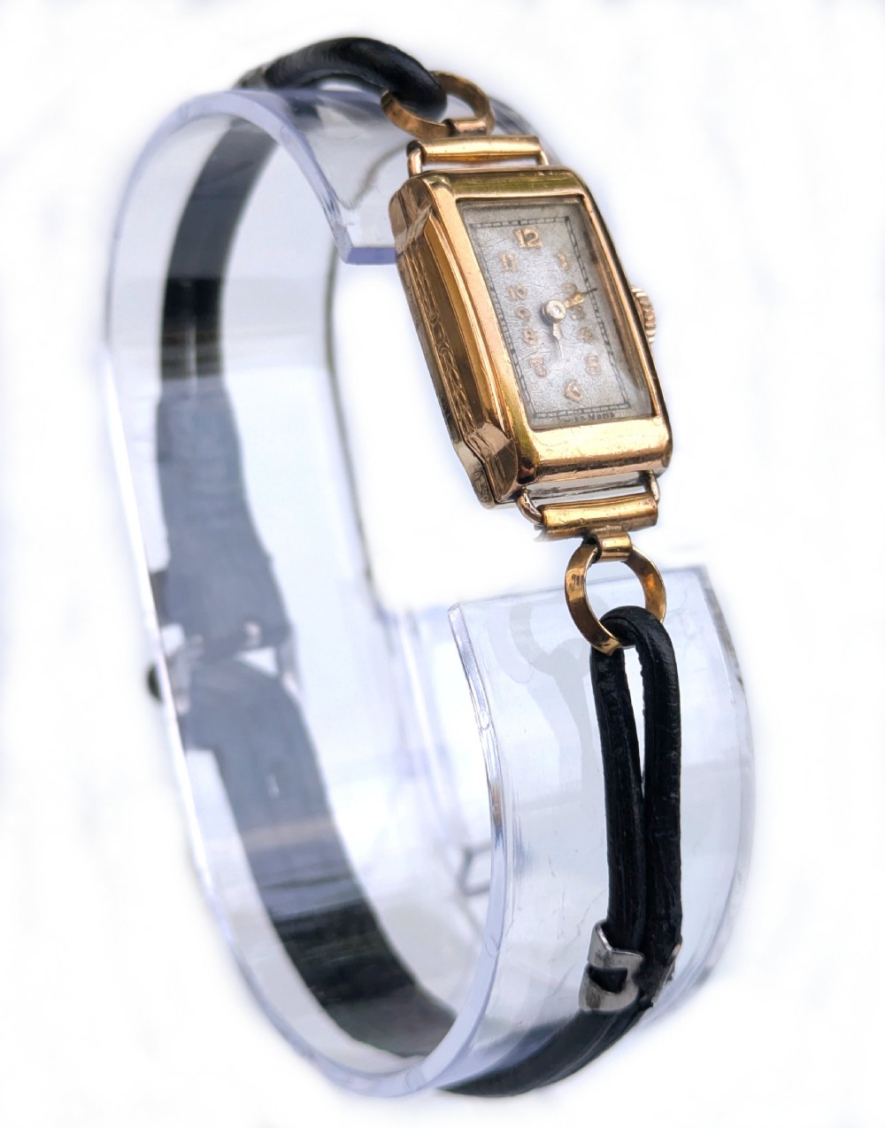 An Art Deco gold-plated ladies wristwatch featuring a rectangular dial, Arabic numerals, and a black cord strap. View V