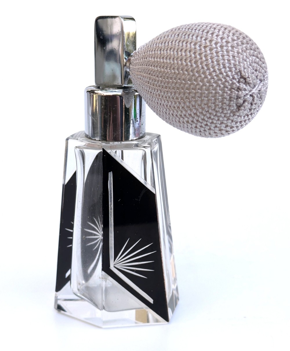 A geometric clear glass Art Deco perfume atomiser bottle featuring black enamel panels, etched sunburst motifs, a chrome spray nozzle, and a grey woven fabric bulb. View VII
