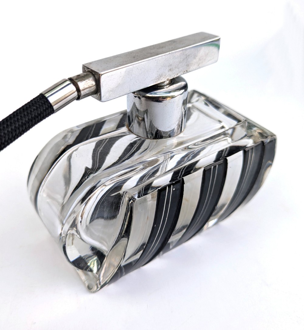 An Art Deco clear glass perfume atomiser featuring painted black geometric stripes, chrome metal hardware, and a black fabric squeeze bulb with a long tassel. View VI