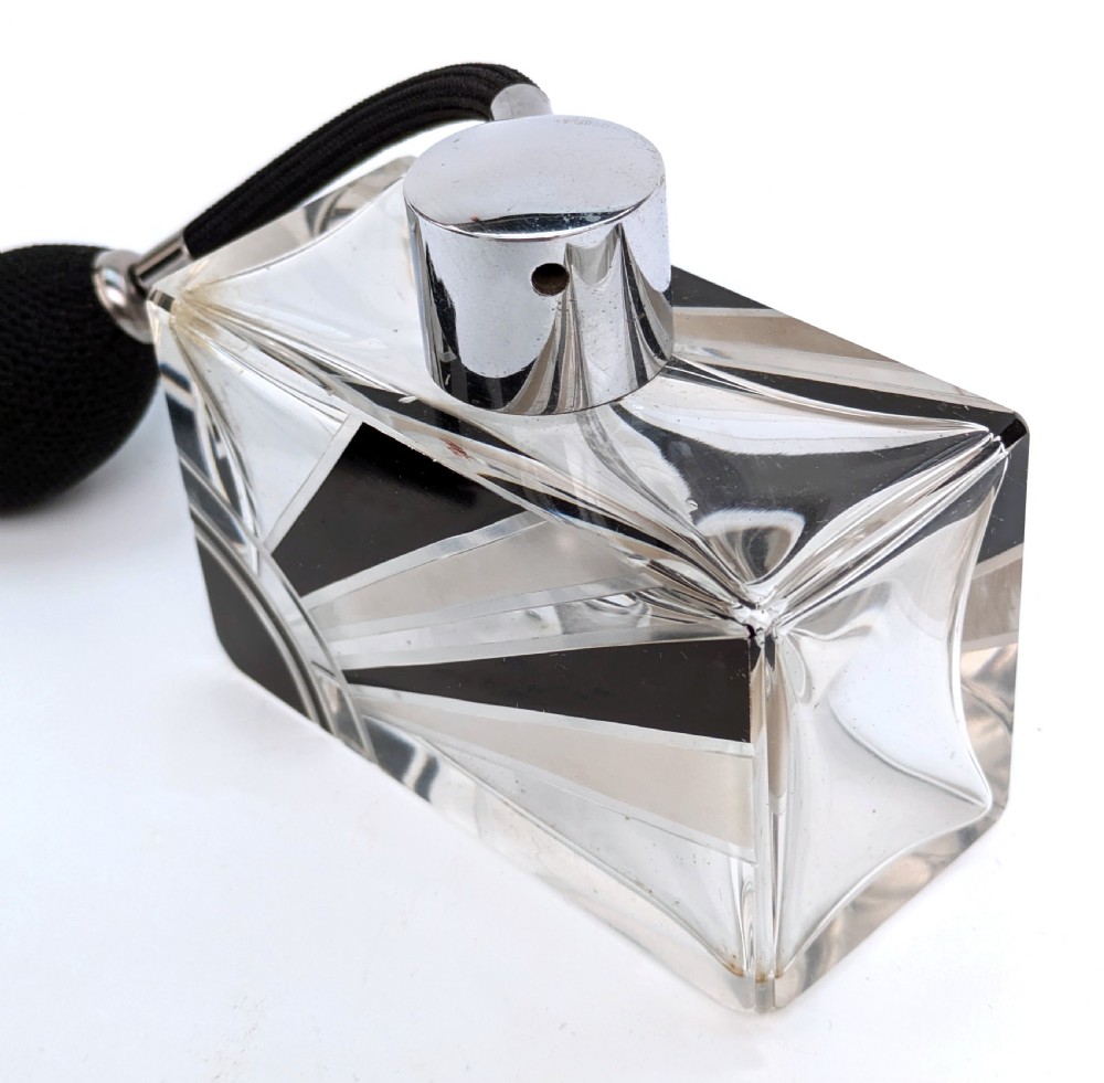 An Art Deco rectangular cut glass perfume atomiser featuring a black enamelled sunray pattern and a chrome top connected to a black fabric bulb with a tassel. View IV