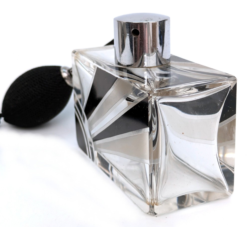 An Art Deco rectangular cut glass perfume atomiser featuring a black enamelled sunray pattern and a chrome top connected to a black fabric bulb with a tassel. View V