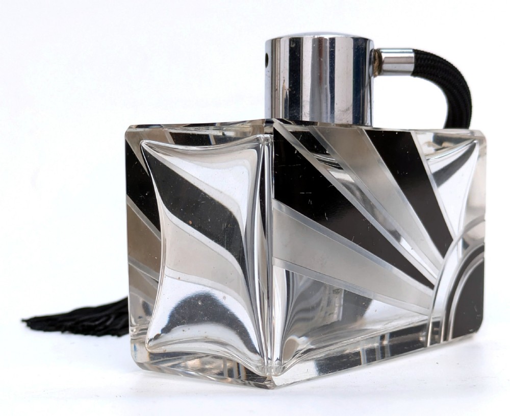 An Art Deco rectangular cut glass perfume atomiser featuring a black enamelled sunray pattern and a chrome top connected to a black fabric bulb with a tassel. View VII