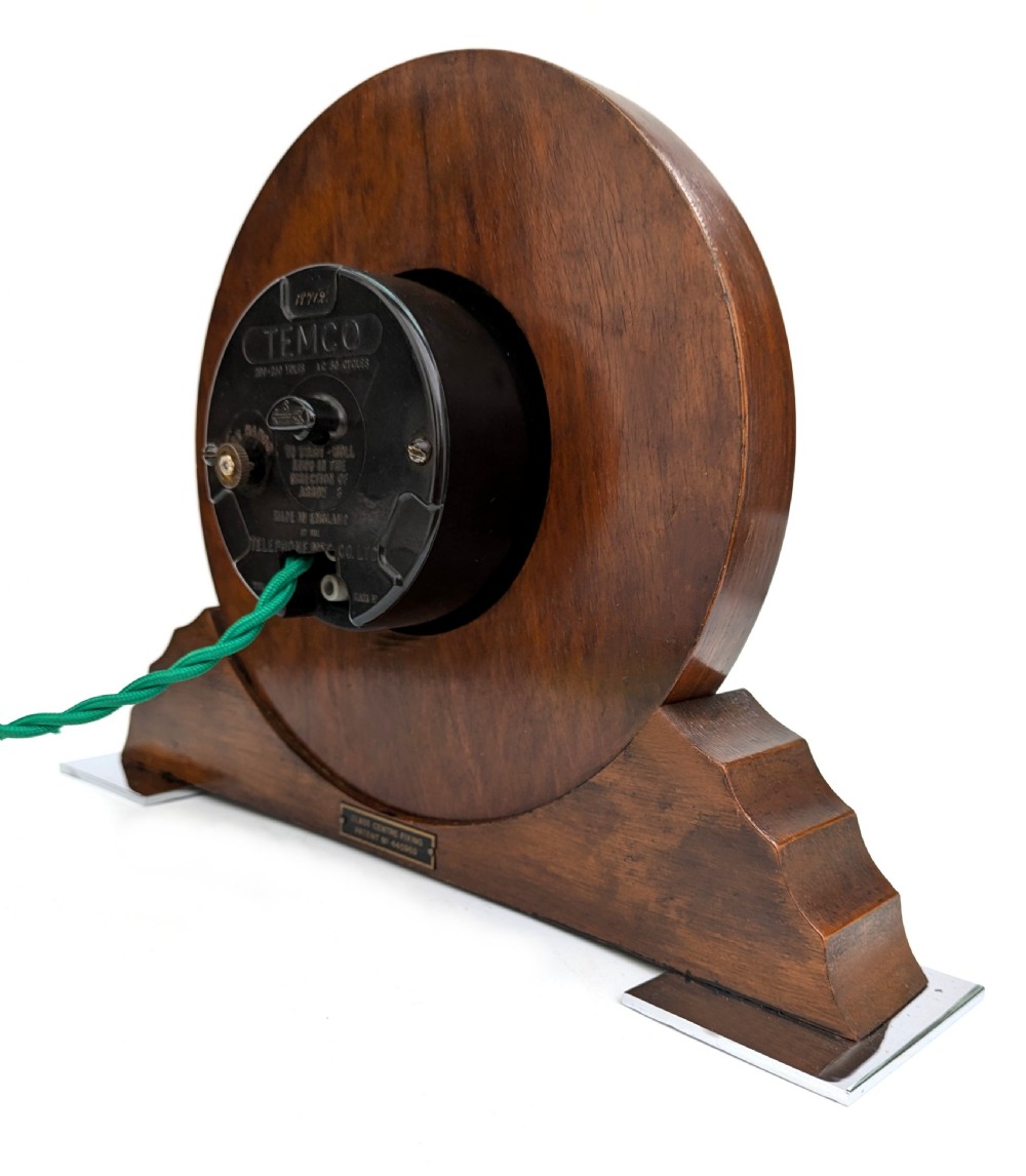 An Art Deco circular walnut mantel clock featuring inlaid Roman numerals and a stepped contoured base. View V