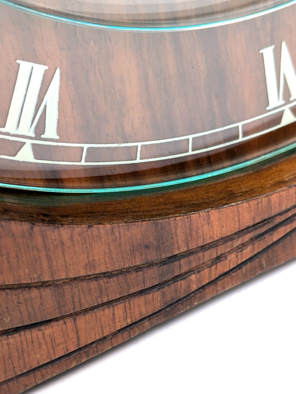 An Art Deco circular walnut mantel clock featuring inlaid Roman numerals and a stepped contoured base. View IX