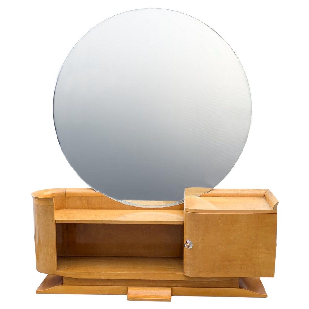 A 1930s Art Deco blonde wood dressing table featuring a massive circular mirror, asymmetrical open shelving, and a curved side pedestal cabinet. View IV